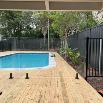 FRAMELESS GLASS FENCING ON TIMBER DECK WITH BLACK SPIGOTS